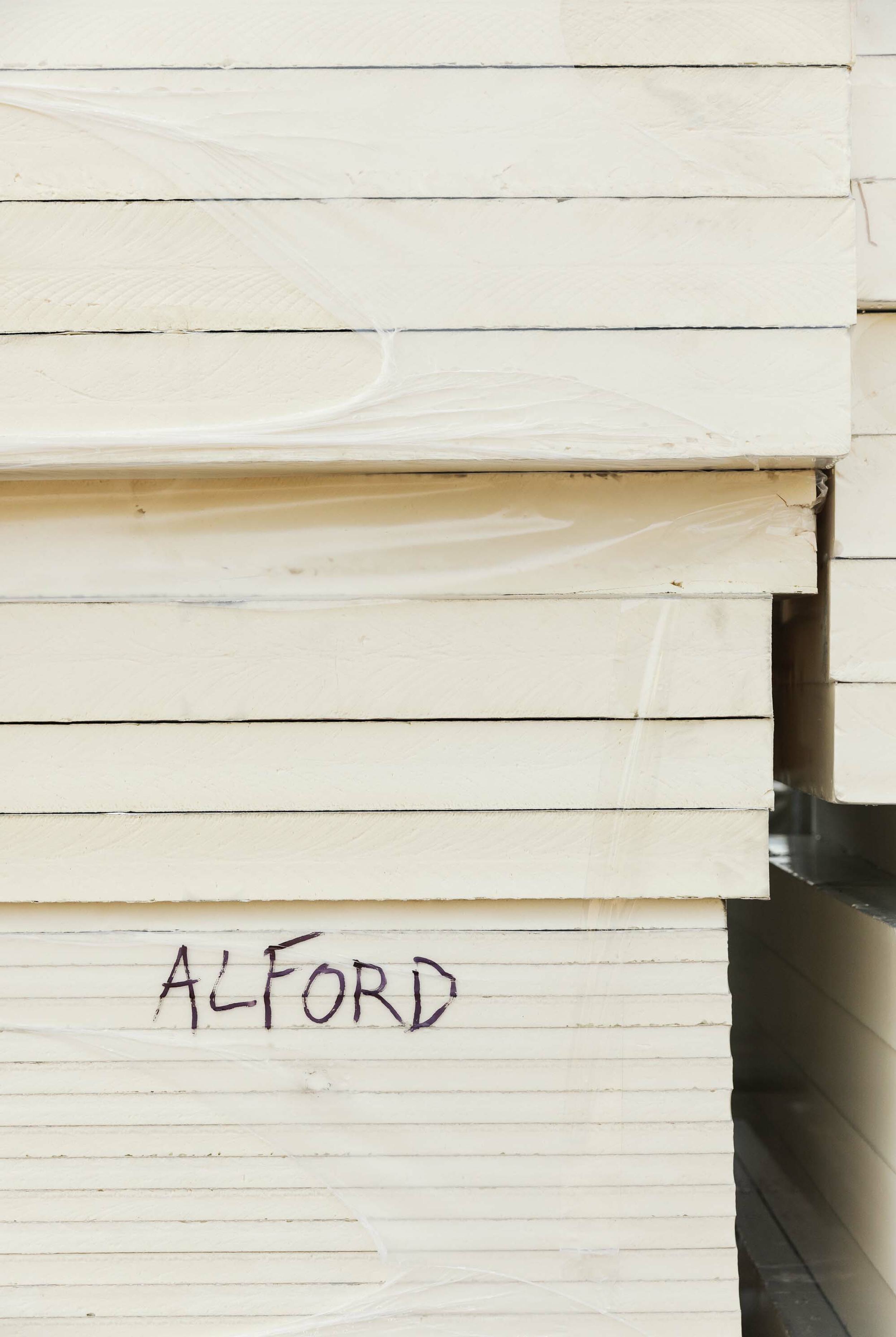 Detail shot showing the edge of PIR insulation stacked in a pile. The location, ‘Alford’ is written in permanent marker on the side on the insulation.